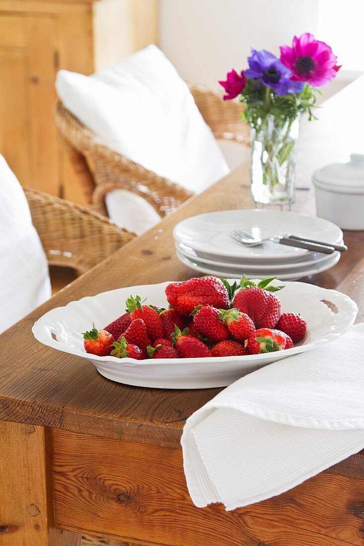 Frische Erdbeeren in weißem Porzellanteller auf Vintage-Holztisch