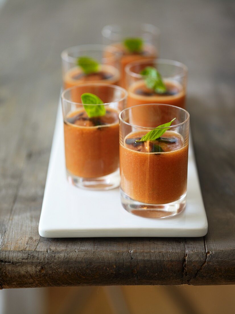 Several glasses of gazpacho with basil