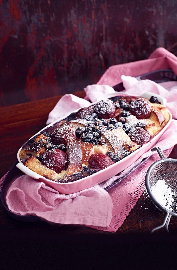 A sweet bake made with brioche, blueberries and plums in a baking dish