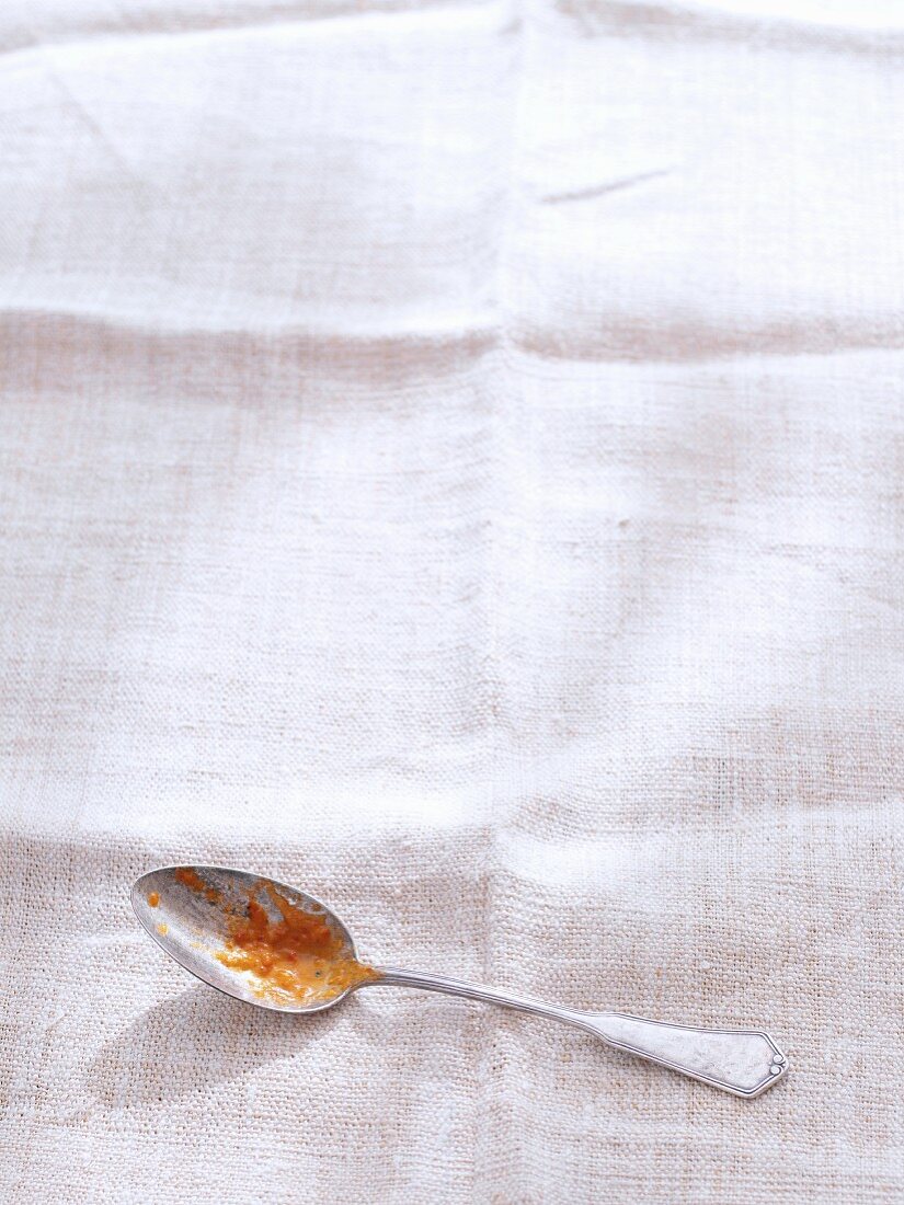 A spoon with the remains of food on a white linen cloth