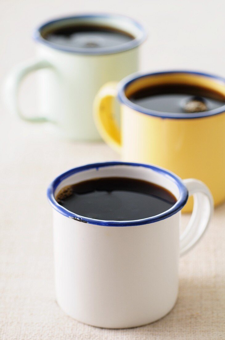 Black coffee in three enamel mugs
