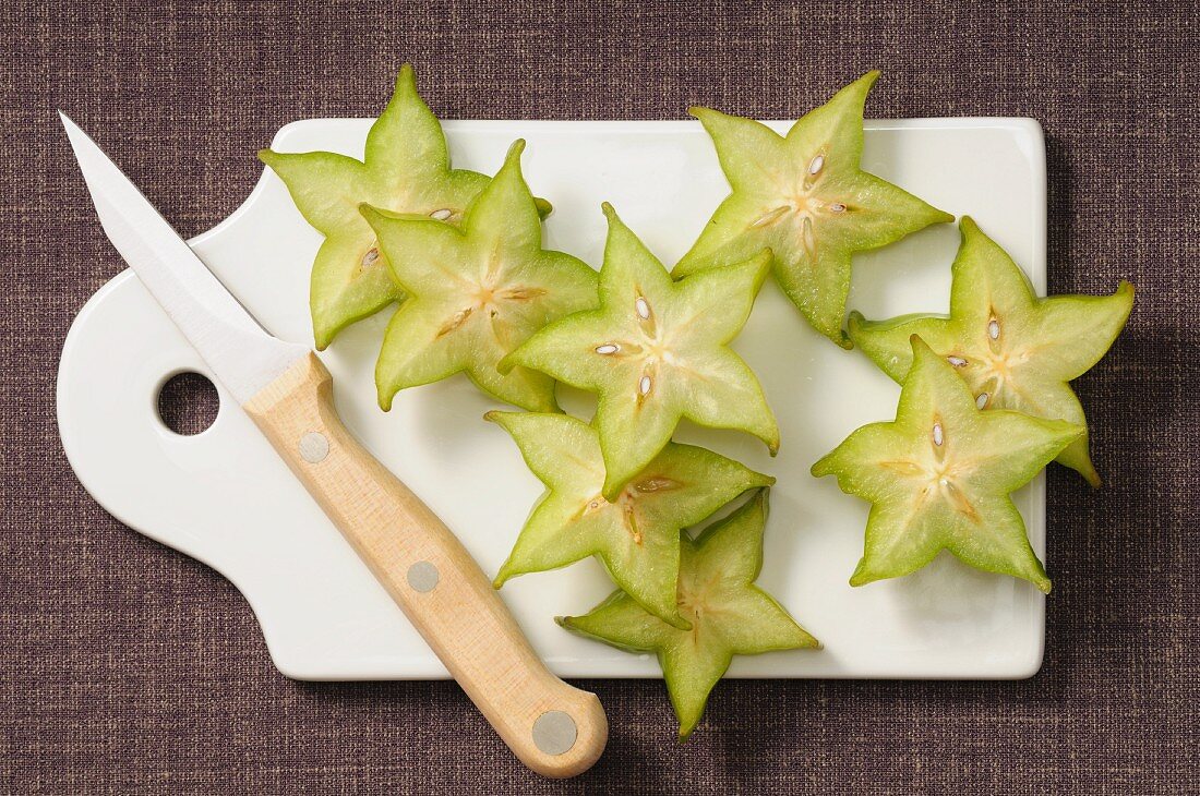 Lots of slices of starfruit on a chopping board