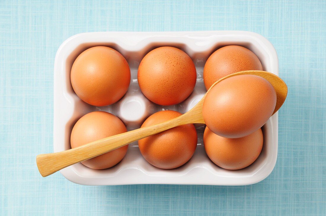 Braune Eier im Behälter und auf Löffel (Draufsicht)