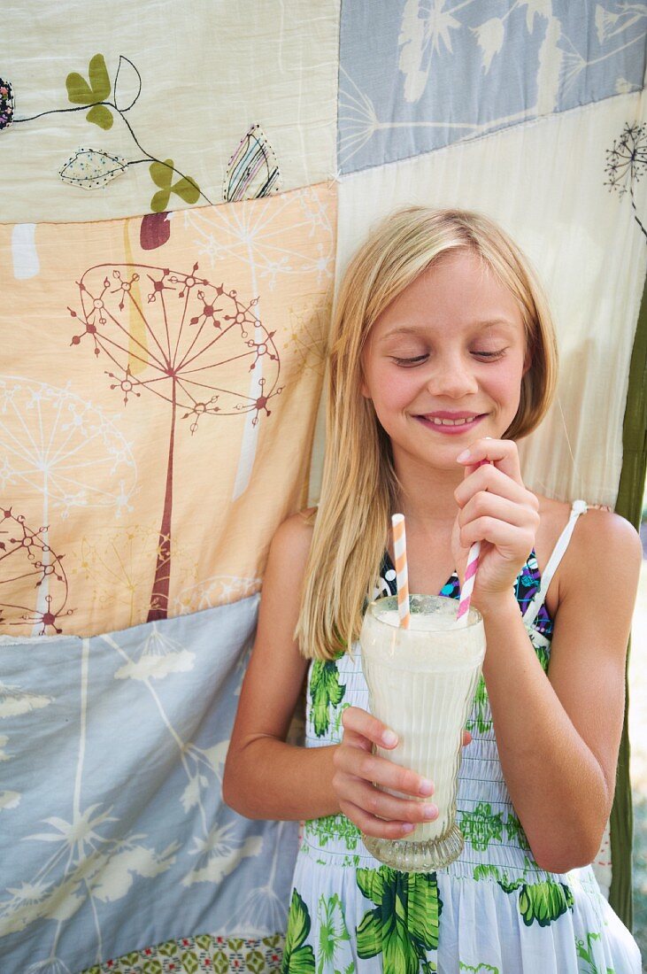 A Young Girl Holding a Milkshake with Two Straws