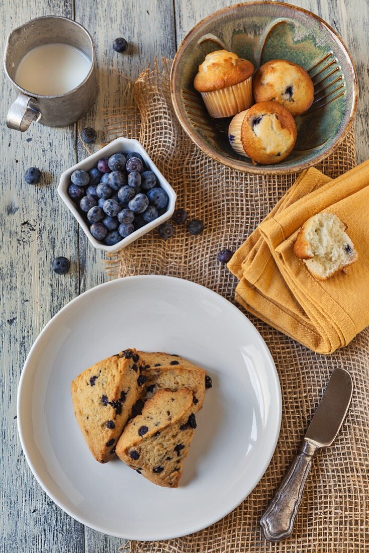 Fresh Blueberries with Blueberry Scones and Blueberry Muffins on a Wooden Table; From Above