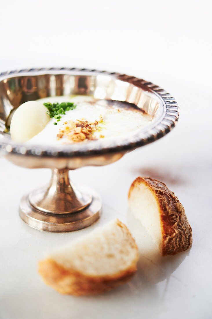 Blumenkohl-Dip mit gehackten Nüssen und Schnittlauch in einer Silberschale und Brot