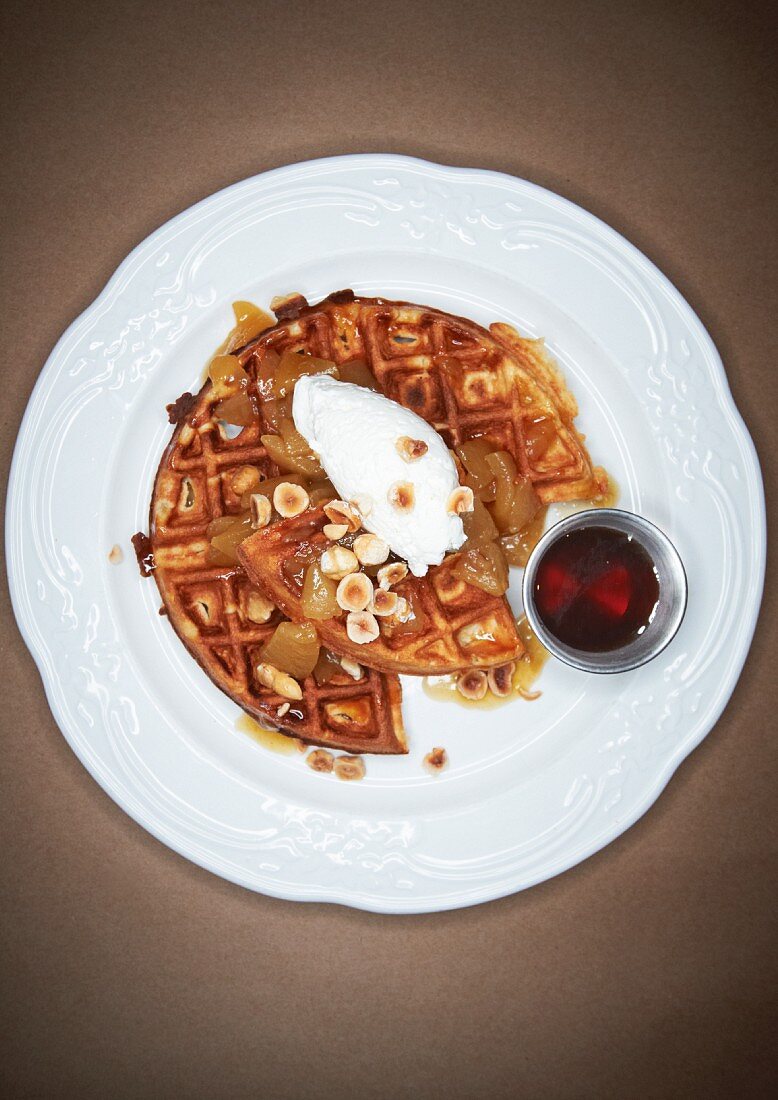 Hazelnut Waffle with Poached Fruit and Chopped Roasted Hazelnuts on a White Plate; Side of Maple Syrup