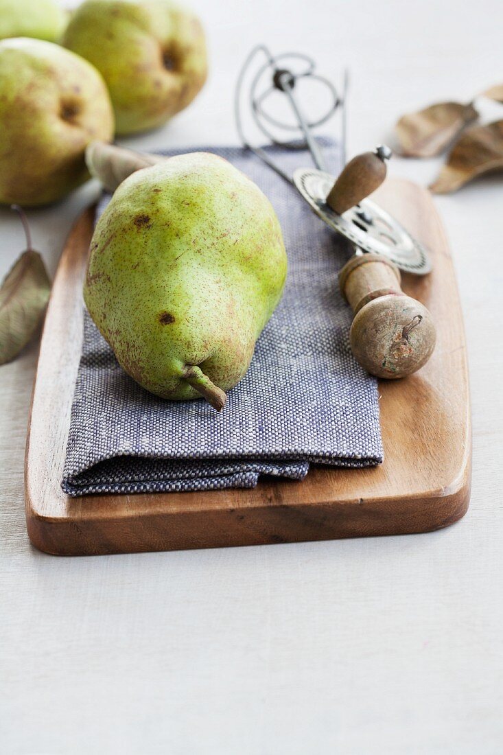 A still life featuring a Williams Christ pear and an old-fashioned whisk
