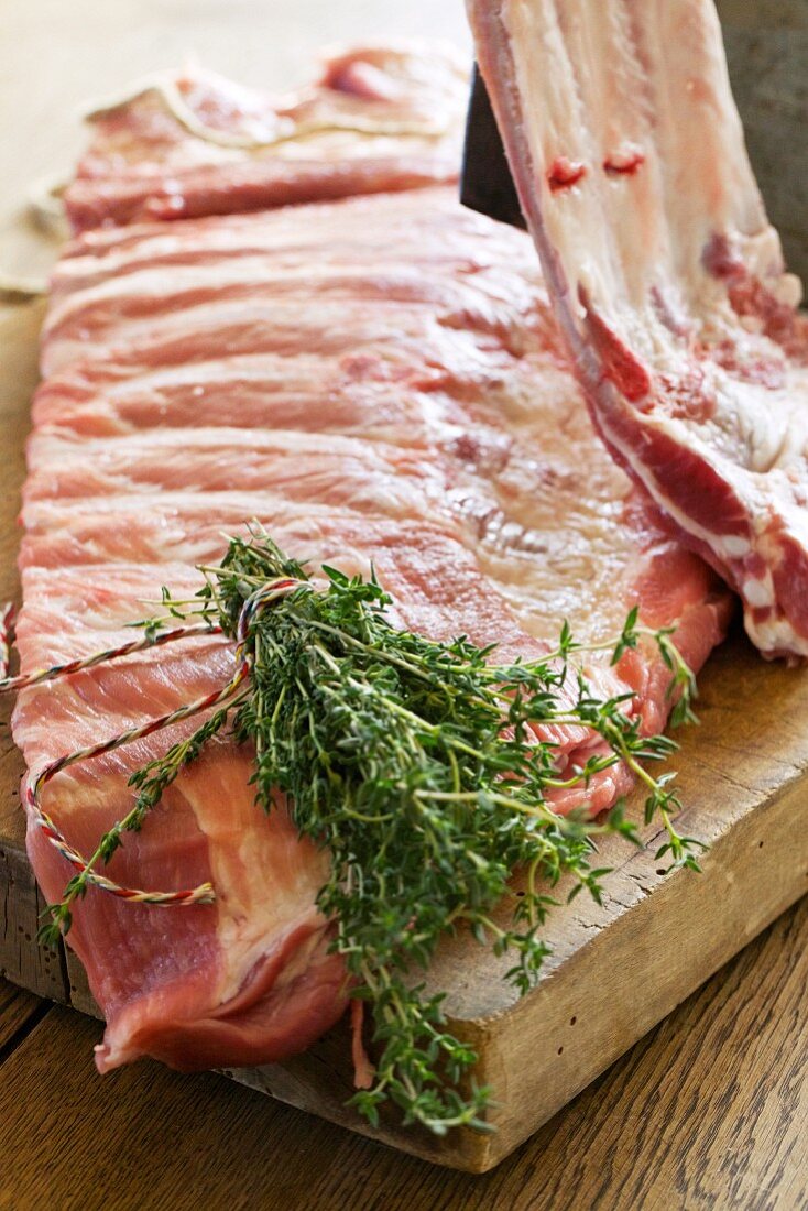 Raw pork ribs with thyme on a wooden board
