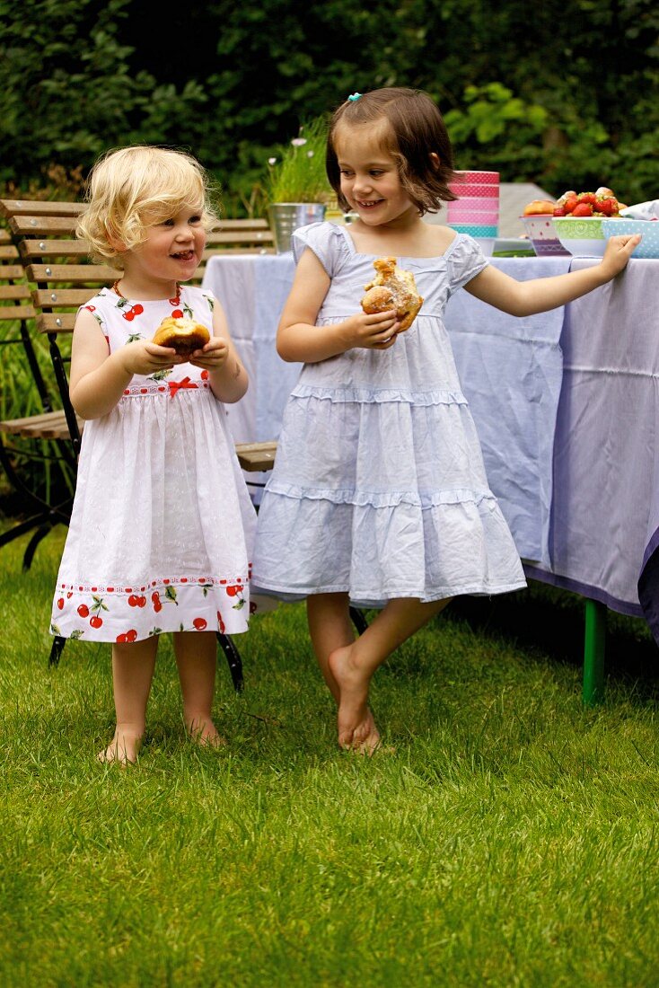 Zwei Mädchen essen Kanelbullar (Schwedische Zimtschnecken) im Freien