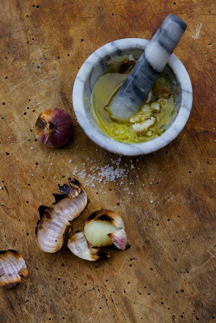 A marinade made from barbecued garlic and oil, in a mortar