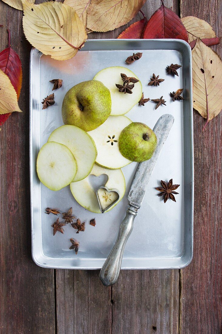 Slices of pear with star anise and a small shaped cutter on a tray