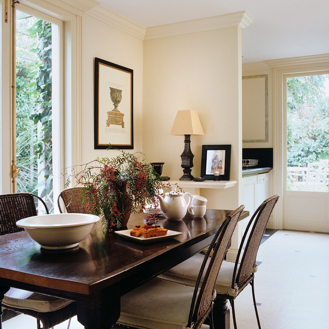 Dark dining table and metal chairs with rattan backs in classic-style, open-plan interior