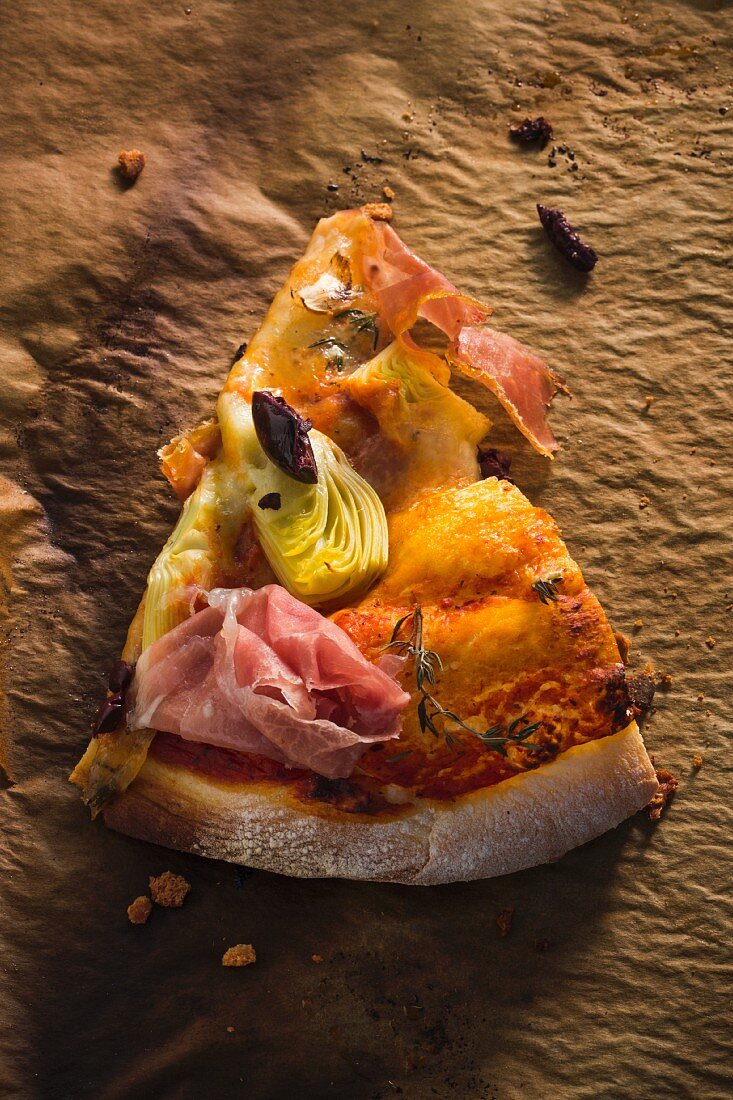Ein Stück Pizza mit Pancetta, Artischocken und schwarzen Oliven