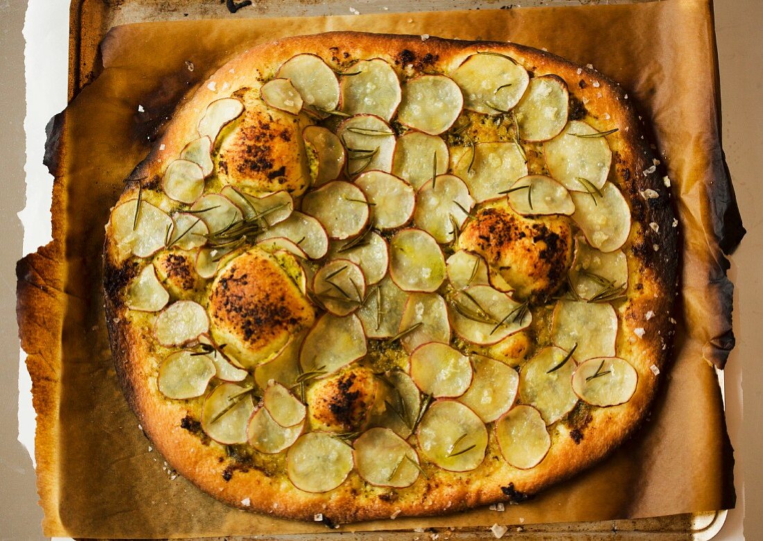 Pizza mit Pesto, dünnen Kartoffelscheiben und Rosmarin (Draufsicht)
