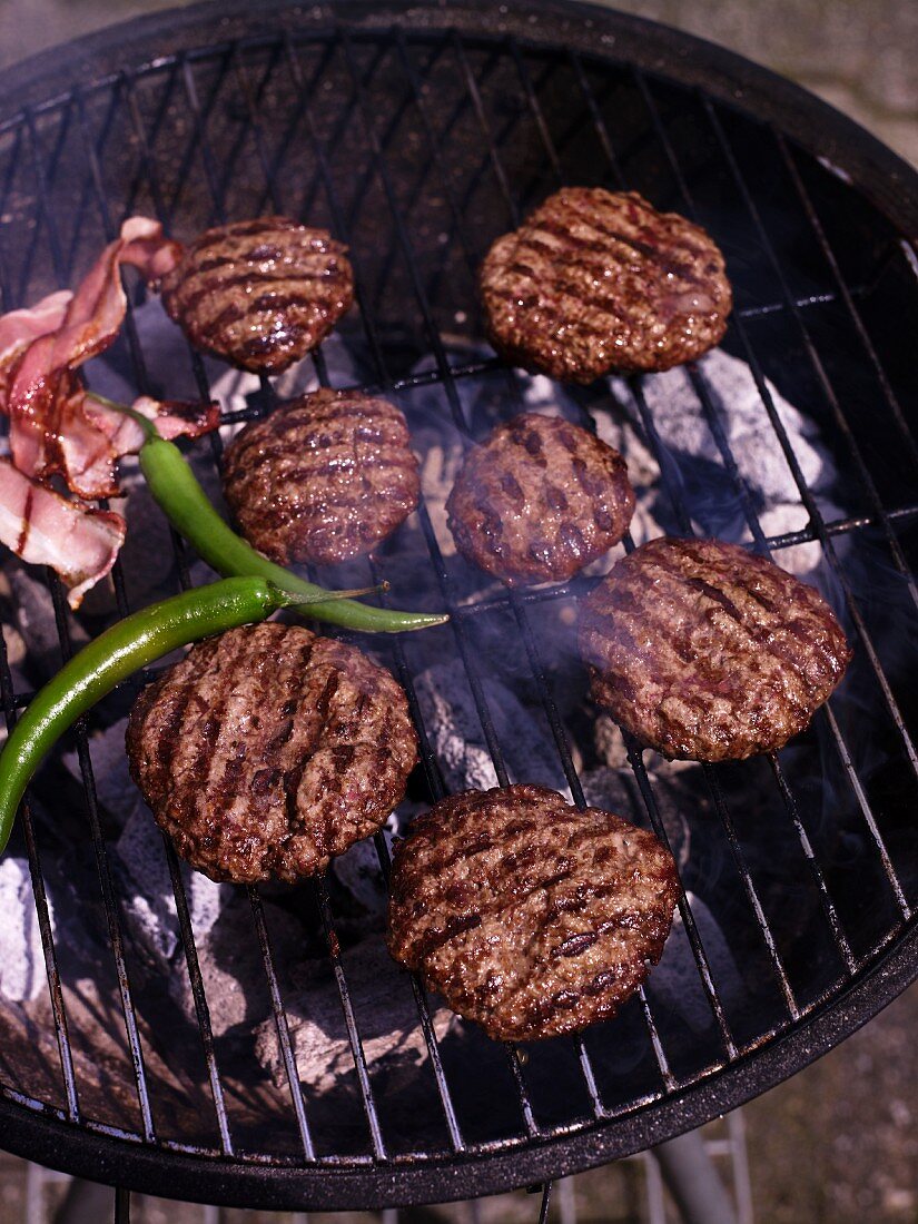 Barbecued burgers, chillies and bacon on the barbecue grill