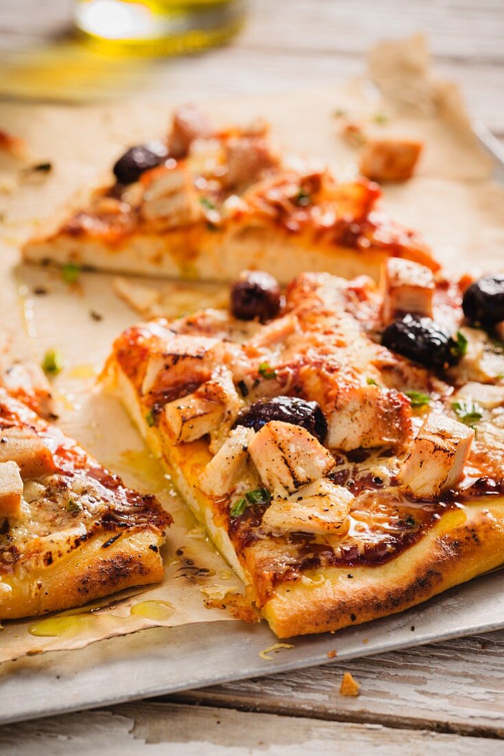 Pizzastücke mit BBQ-Sauce, Hähnchen und schwarzen Oliven