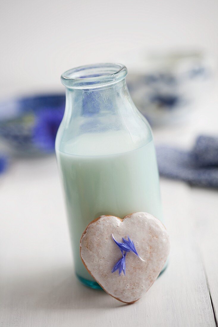 Milk with heart-shaped cinnamon biscuits with sugar glaze and cornflower petals