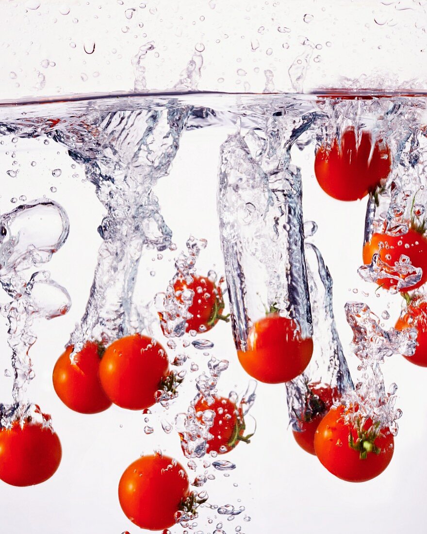 Mehrere Tomaten fallen ins Wasser