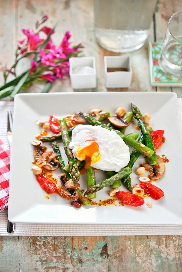 A poached egg with asparagus, mushrooms and tomatoes