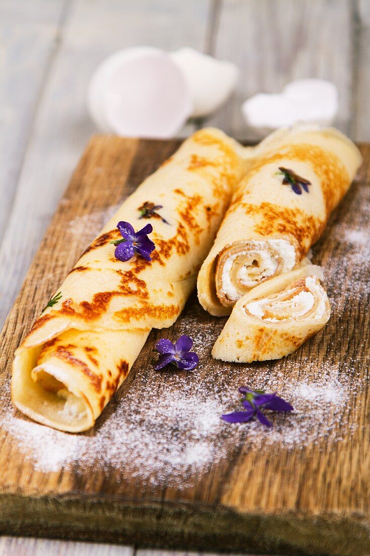 Pancakes filled with cream cheese, with violets