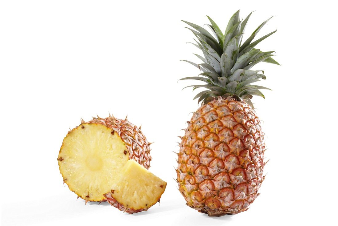 Eine angeschnittene und eine ganze Ananas