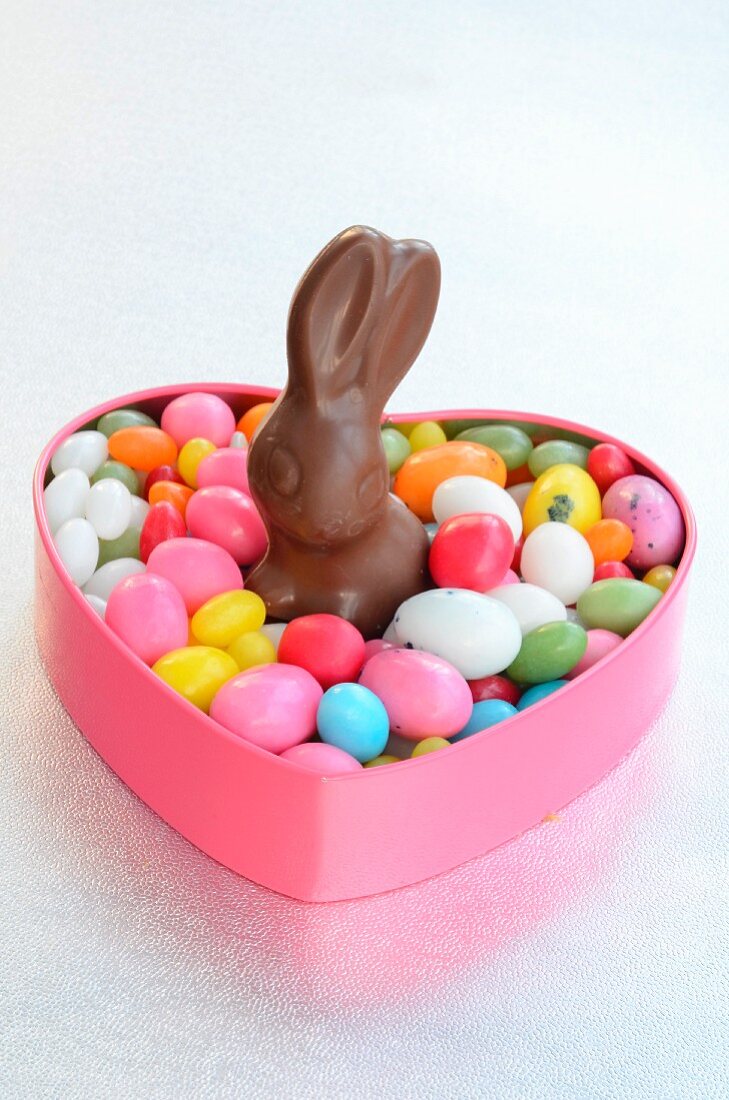 A heart-shaped tin of colourful sugar eggs with a chocolate bunny