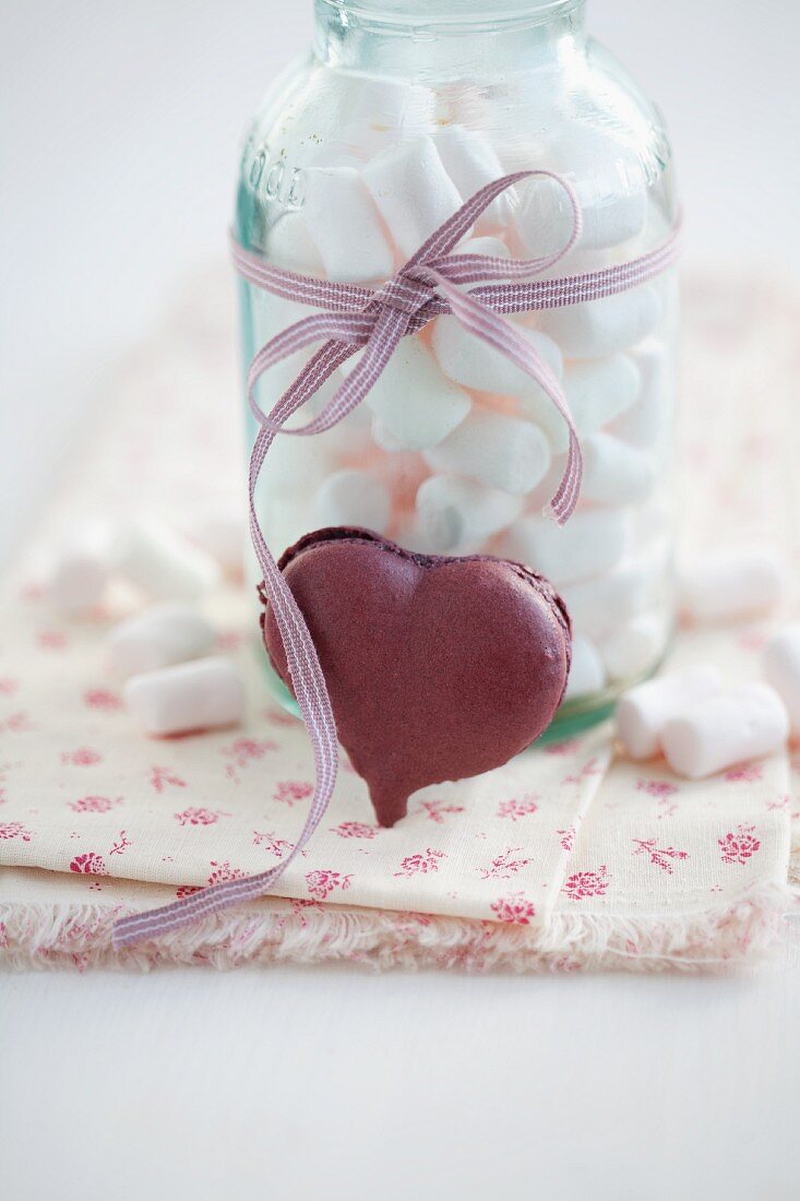 A heart-shaped blackcurrant macaroon and marshmallows in a jar