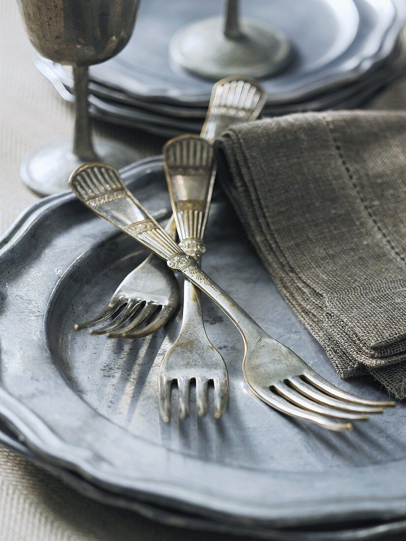 Old silver forks on a pewter plate