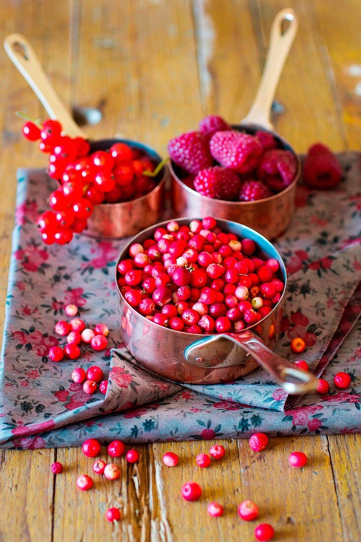Assorted berries in copper saucepans