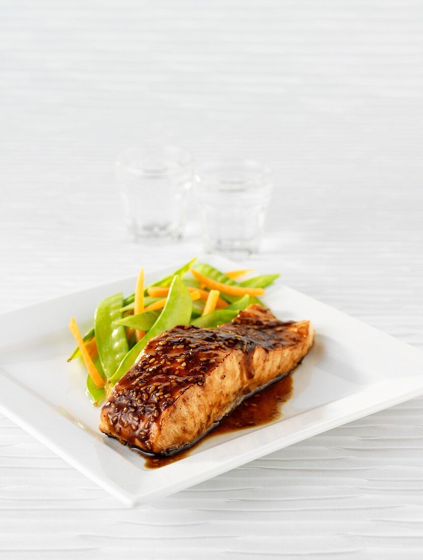 A slice of salmon in teriyaki sauce with vegetables
