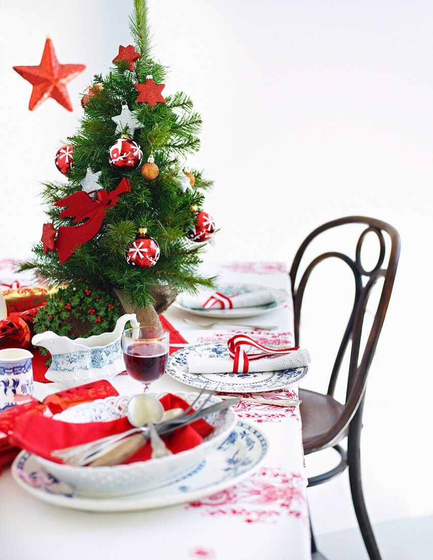A table laid for Christmas dinner decorated with a mini Christmas tree