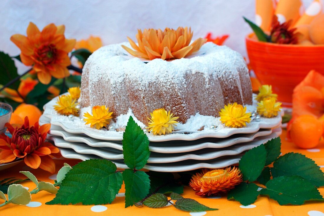 A Bundt cake coated with icing sugar and decorated with orange flowers