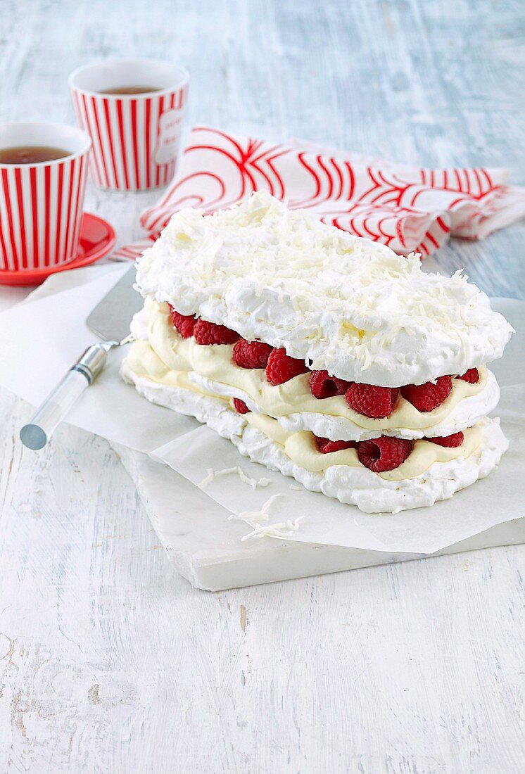 Coconut meringue cake with lime cream and raspberries