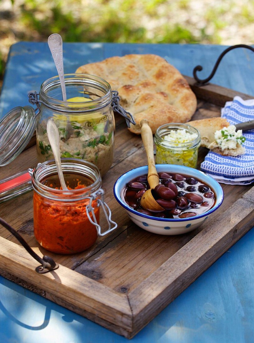 Beilagen zum Grillfest: Oliven, Fladenbrot, Feta-Aufstrich und Saucen (Griechenland)