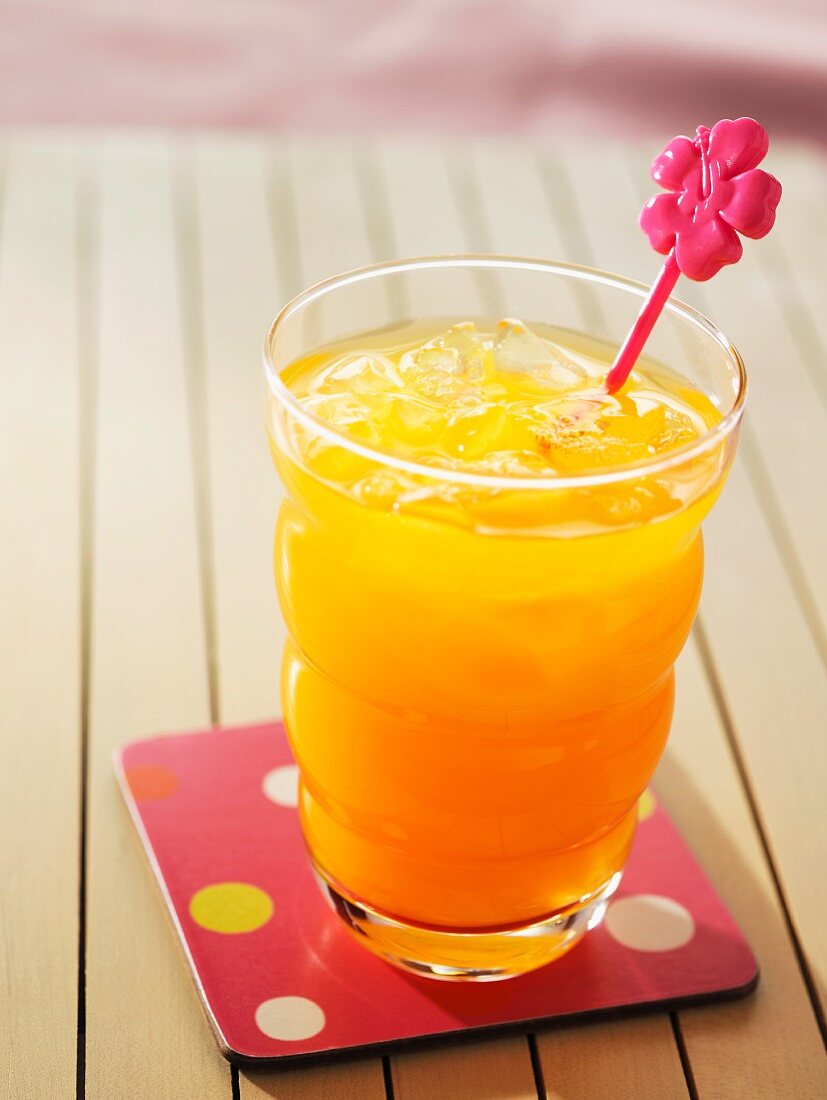 Orange juice with ice and a pink decoration