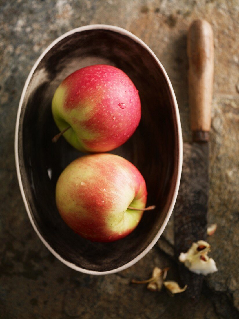 Two Pink Lady apples in a dish