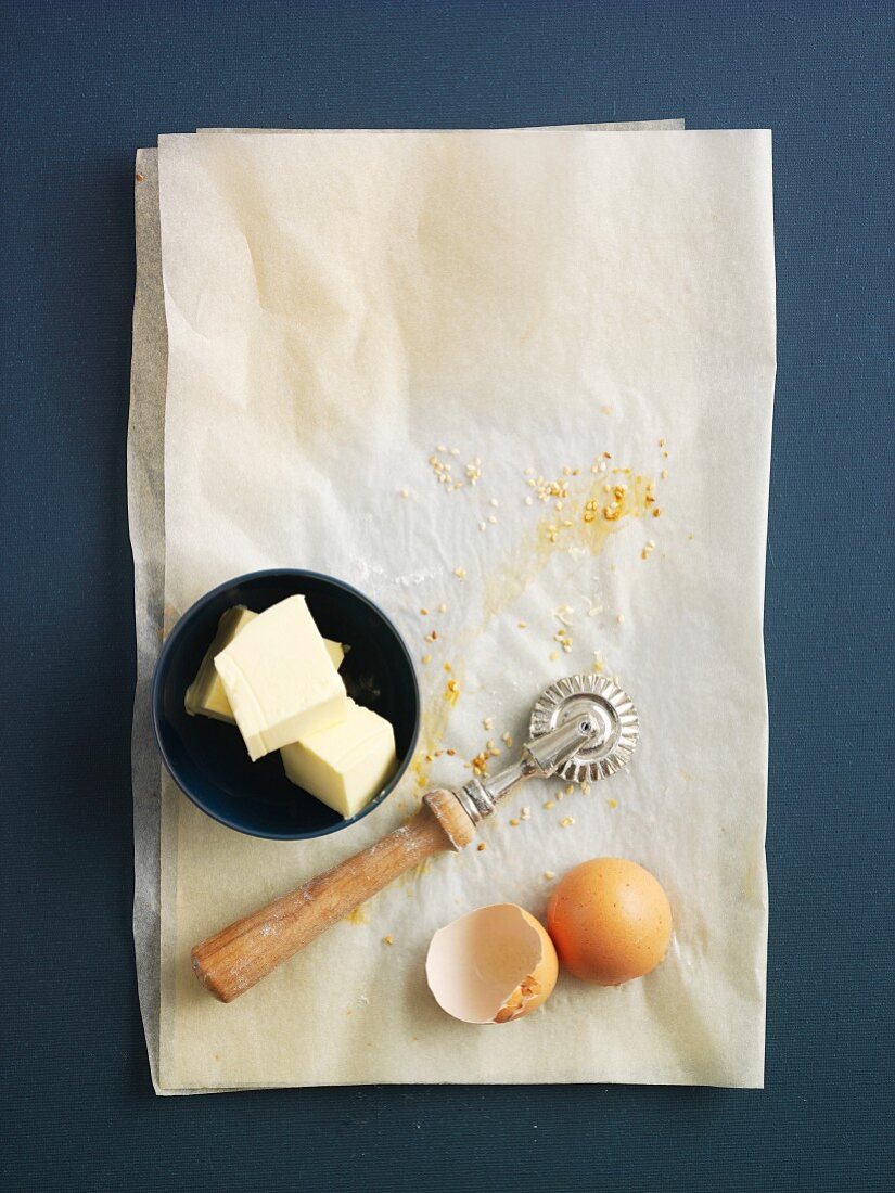 Butter, Teigrädchen und Eierschalen auf Backpapier