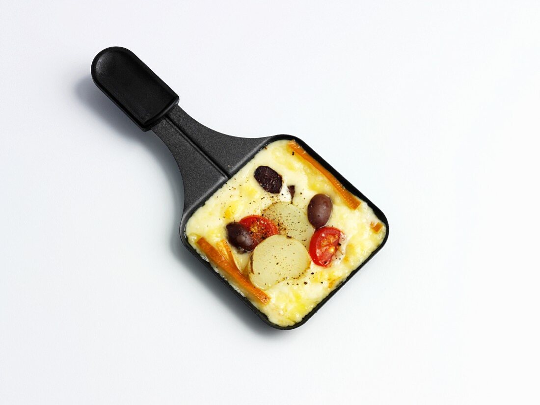 Raclette with potatoes, olives and tomatoes