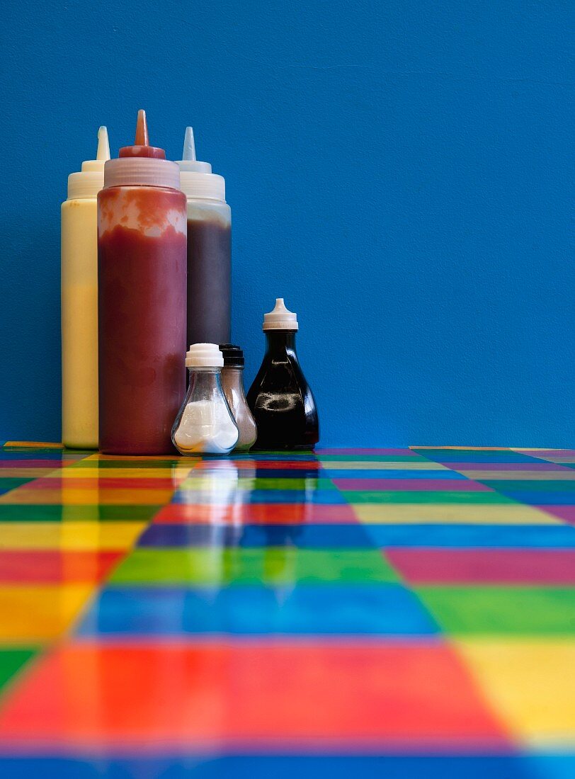 Sauces, salt and pepper pots and seasoning on a colourful restaurant table
