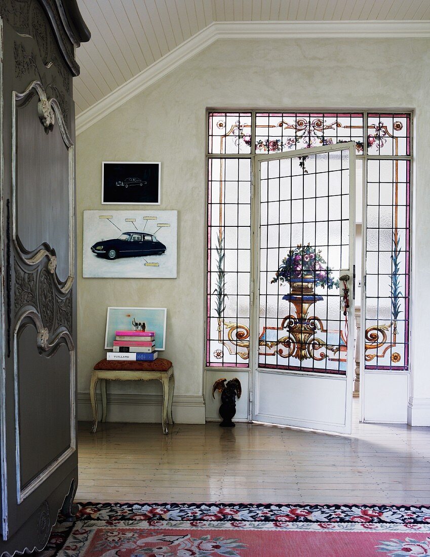 Door element with romantic, painted leaded glass in attic room; antique wardrobe to one side