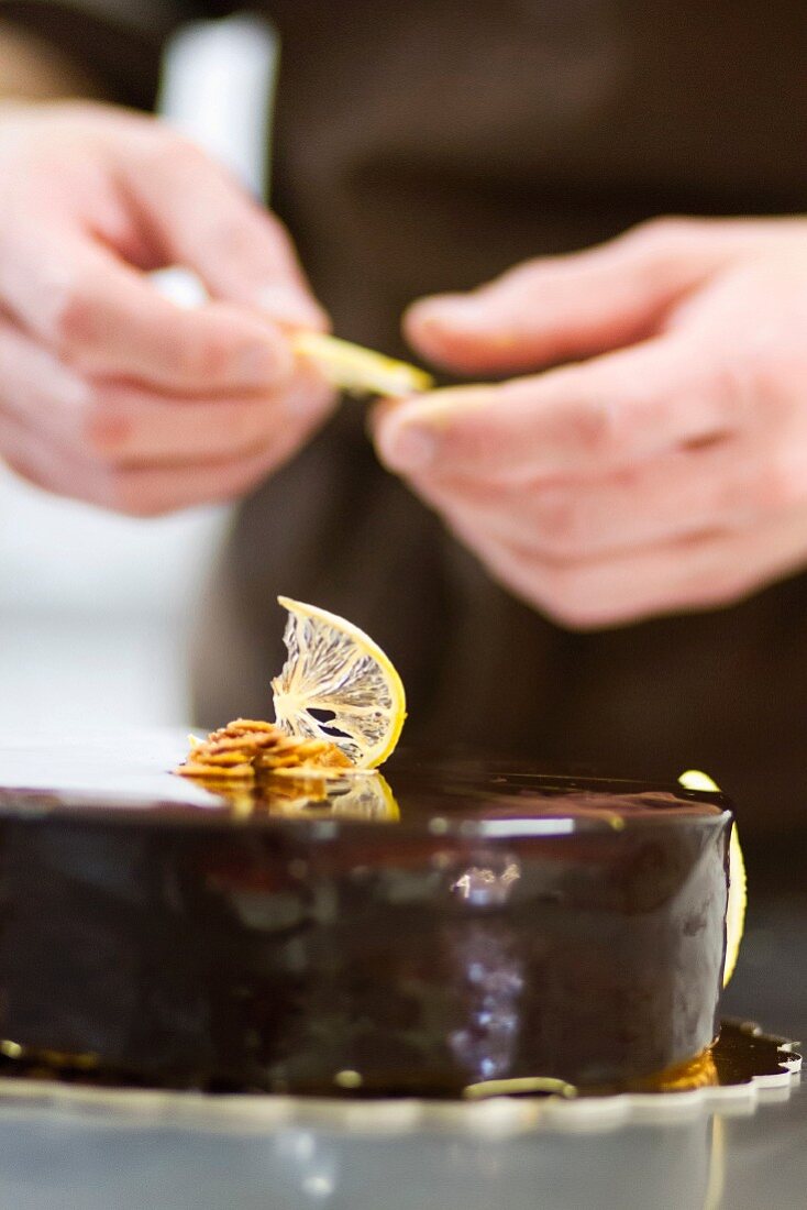 A pastry chef decorates a chocolate tart