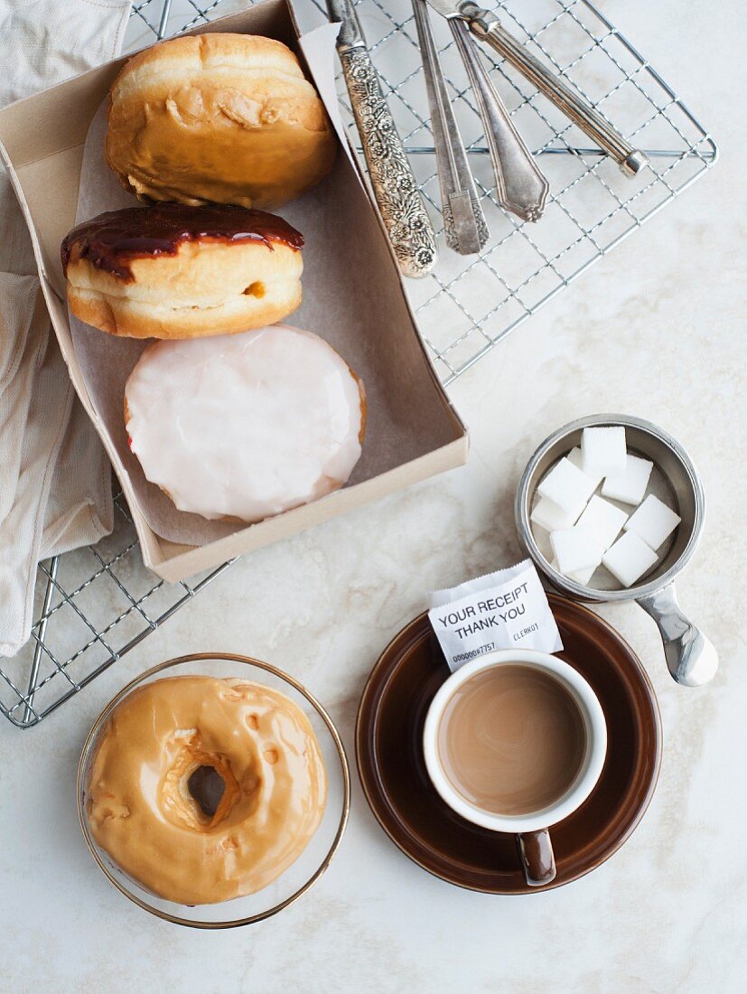 Krapfen & Donuts neben einer Tasse Kaffee (Aufsicht)