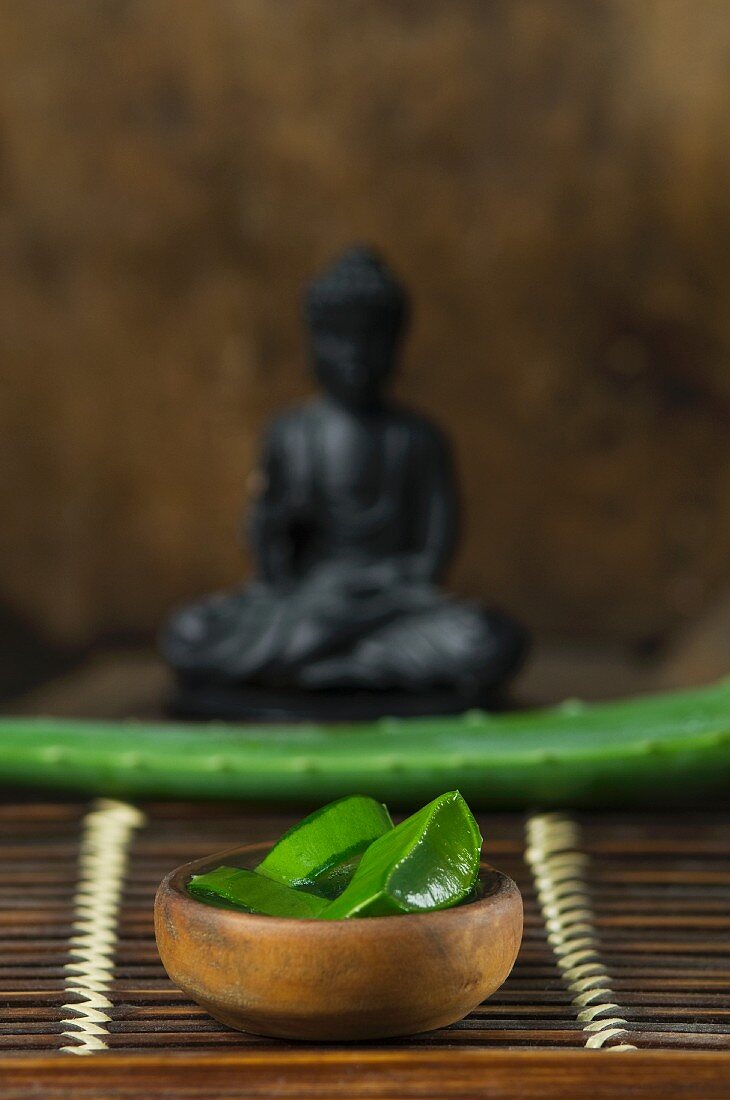 Sliced aloe vera shoots in front of a Buddha figurine