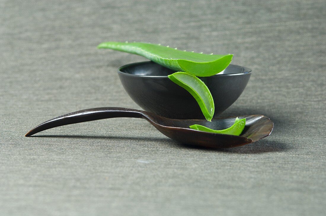 Sliced aloe vera shoots with a bowl and a wooden spoon