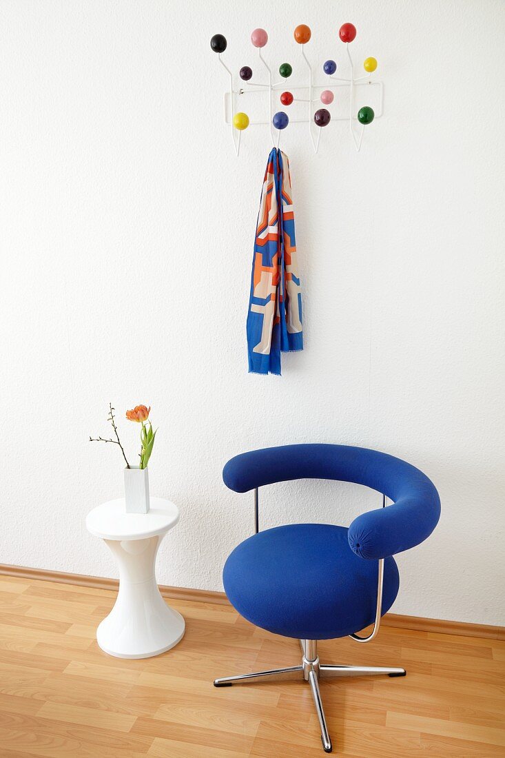 Bauhaus swivel chair with blue cover and side table in front of classic, wall-mounted coat rack