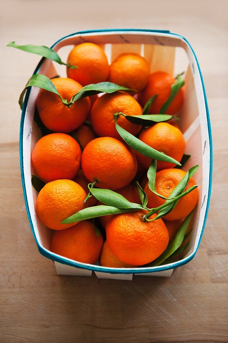 Fresh clementines with leaves in a woodchip basket