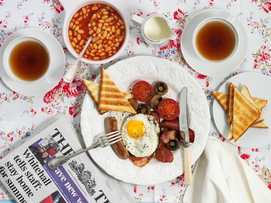 Englisches Frühstück mit Bacon, Spiegelei, Toast, Baked Beans und Tee