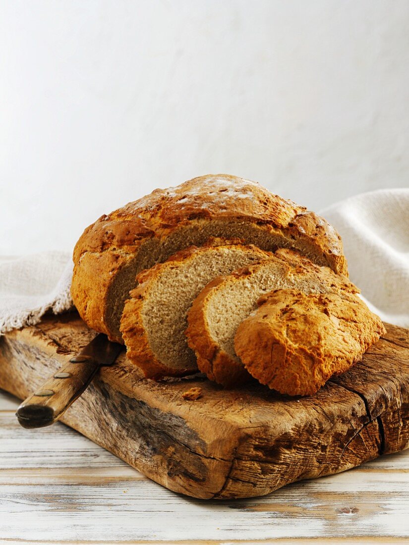 Klassisches Hefe-Mischbrot, angeschnitten, auf Holzbrett