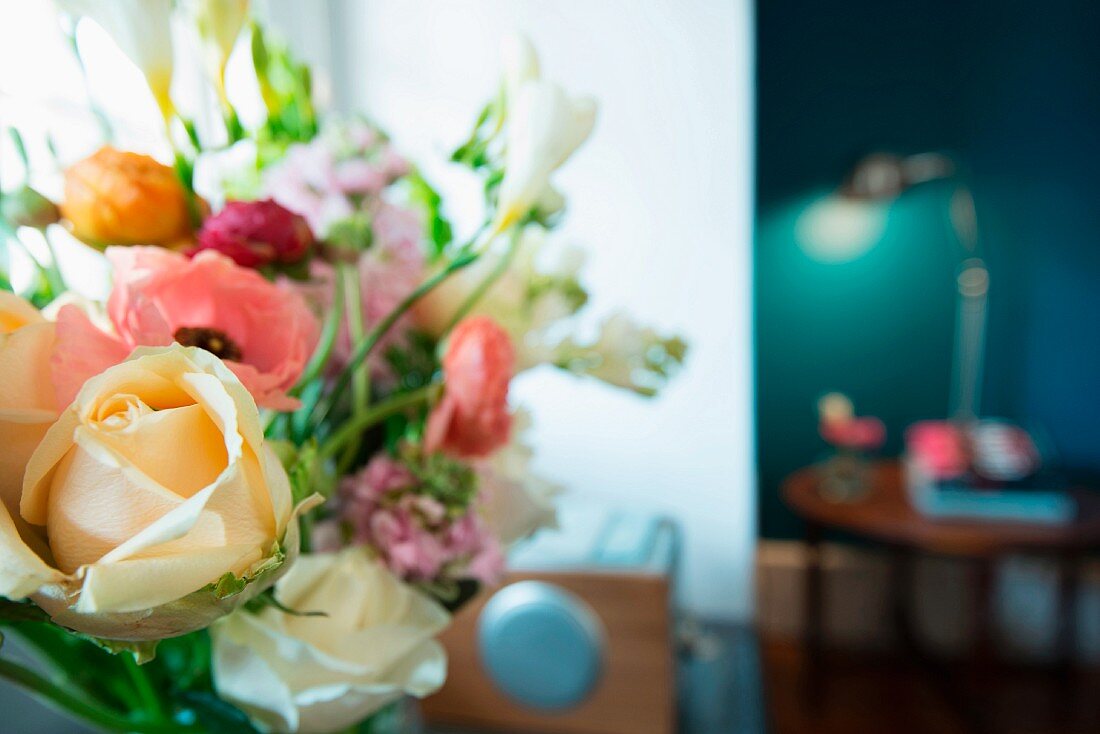 Bouquet of ranunculus, freesias and roses in delicate shades against blurred background